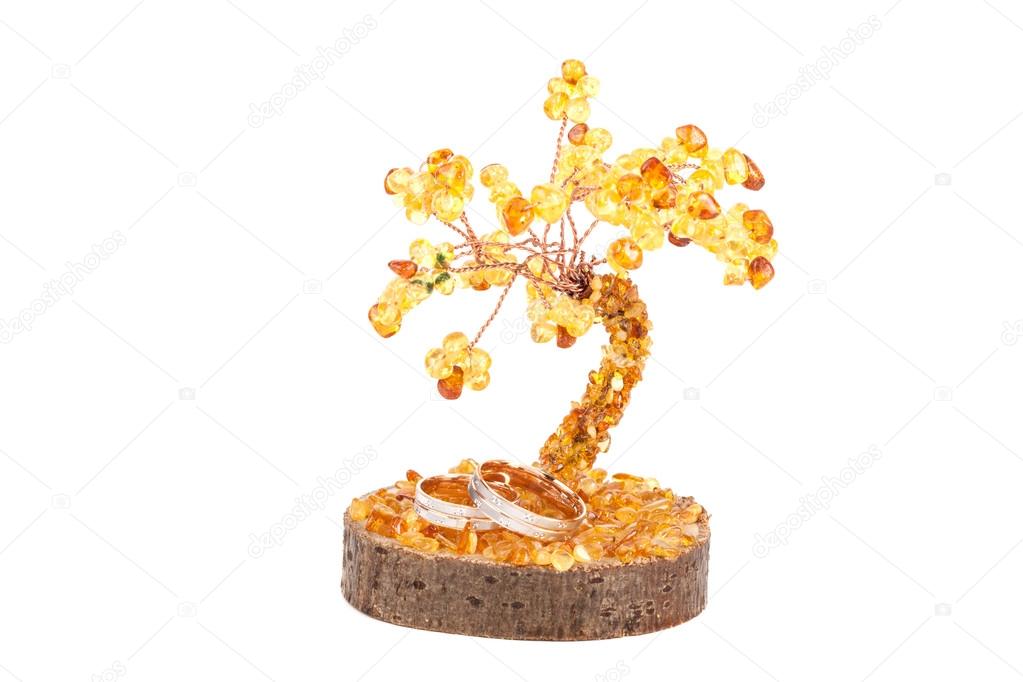 Amber tree of happiness and wedding rings isolated on white back