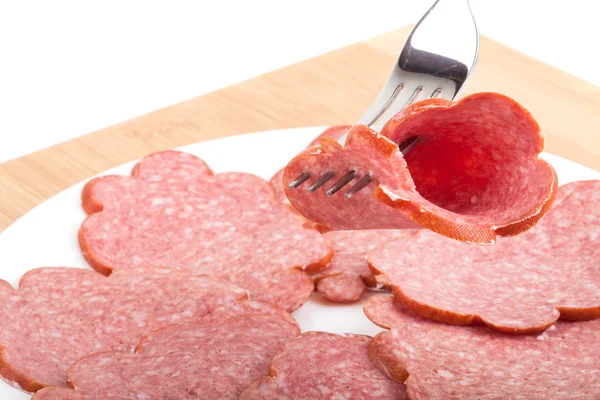 A piece of sausage and fork on wooden board isolated on white ba — Stock Photo, Image