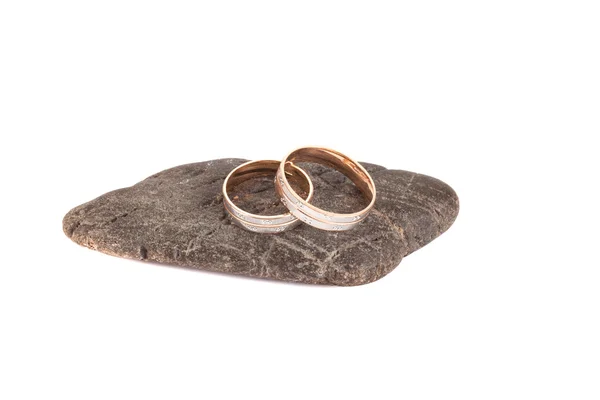 Anillos de boda en una piedra sobre un aislamiento de fondo blanco —  Fotos de Stock