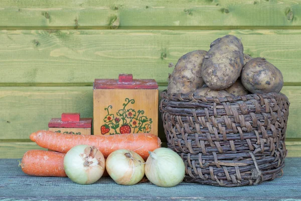 Fresh potatoes in an old basket, carrots, onions and old boxes — Stock Image Fresh potatoes in an old basket, carrots, onions and old boxes Stock Photo