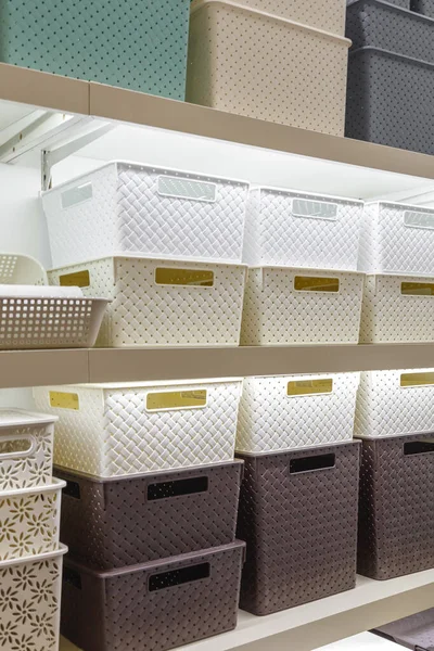 Plastbehållare lådor på en hylla på en rack för att organisera hem utrymme och lagra saker, ordning och inredning, sälja hushållsartiklar. Industriell bakgrund Stockbild