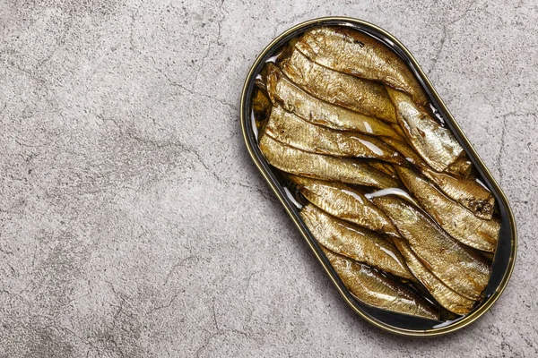 Food, canned fish in a tin can, smoked sprats in oil on a table background with copy space top view.
