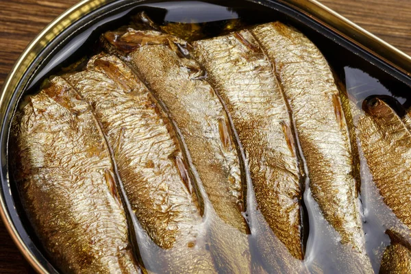 Food background, canned fish in a tin can, sprats smoked in oil seafood close-up top view.