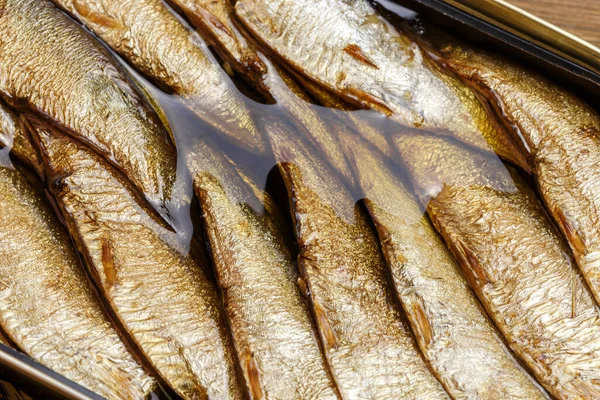 Food background, canned fish in a tin can, sprats smoked in oil seafood close-up top view