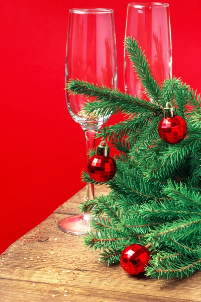 Natale auguri di Capodanno biglietto di auguri con bicchieri di vino, abete, scintille d'oro, ghirlanda incandescente su sfondo rosso — Foto Stock