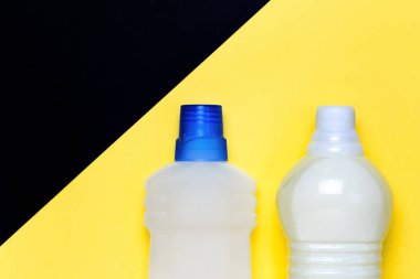 Fotokopi alanı olan parlak sarı arkaplandaki bir şişedeki deterjanı temizleyin. Temizlik ve ev işleri için ev yapımı kimyasallar. Üst görünüm için ambalaj