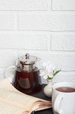 Sabah çayı. Mutfak masasında açık eski bir kitap ve bir fincan çay. Konforlu bir tavan arası odasında rahatça kitap okumak.