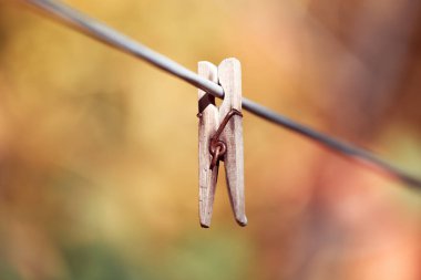 Keten bir ipe bağlanmış eski bir mandal. Evde çalış, çamaşır yıka, çarşaf kurula. Soyut sarı turuncu sonbahar arka planı. Modası geçmiş unutulmuş şeyler kavramı