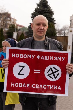 KISHINEV, MOLDOVA - 29 Mart 2022: Ukrayna 'yı desteklemek için halk toplantısı. Rusya Federasyonu büyükelçiliğinin yanında Ukrayna bayrakları ve posterleri olan insanlar. Faşizmin sembolü..