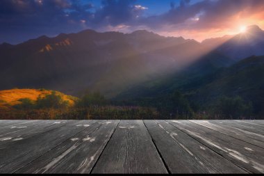 Dağların üzerinde güzel bir gün doğumu ve doğadaki boş ahşap masa. Doğal şablon manzarası.