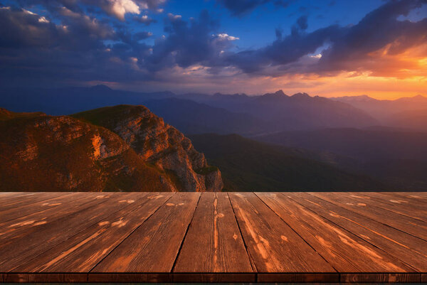 Beautiful sunrise over mountains and empty wooden table in nature outdoor. Natural template landscape.