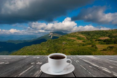 Kahve fincanı ahşap masada ve güzel doğa manzaralı..