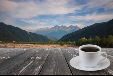 Kahve fincanı ahşap masada ve güzel doğa manzaralı..