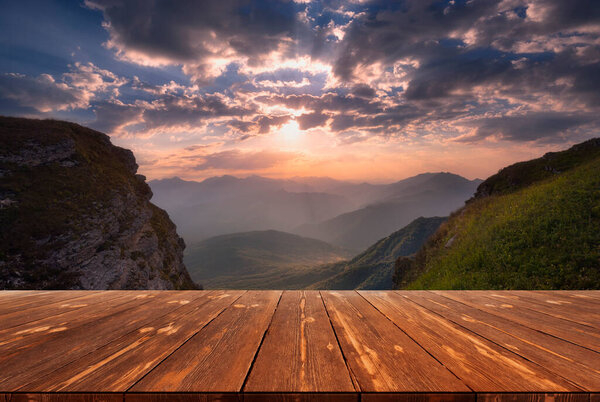 Summer beautiful background with sunrise over mountains and empty wooden table in nature outdoor. Natural template landscape.