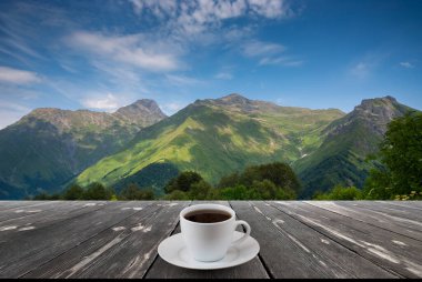 Kahve fincanı ahşap masada ve güzel doğa manzaralı..