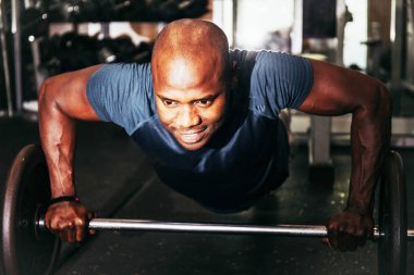 Bir zencinin ağırlık kaldırma çubuğuyla şınav çekerken çekilmiş resmi. Spor ve eğlence.