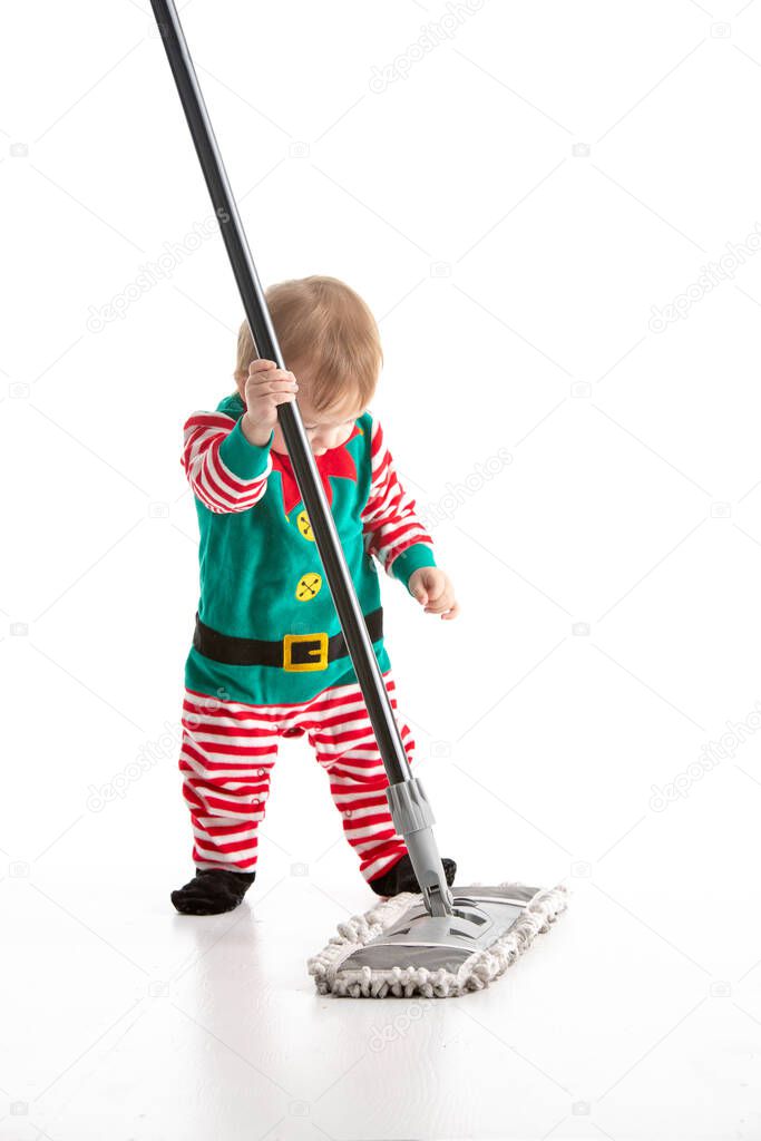 Stock studio photo with a white background of a baby disguised as an elf clinging to the stick of a mop