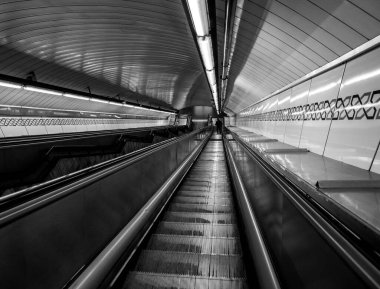 Metro istasyonunun girişinde mekanik merdivenli siyah beyaz fotoğraf. Taşıma kavramı.