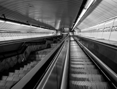 Metro istasyonunun girişinde mekanik merdivenli siyah beyaz fotoğraf. Taşıma kavramı.
