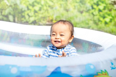 Oğlan yazın ortasında sıcak bir günde evde havuz başında mutlu mesut oynuyor. Gülümsemenin güzel çocuğu..