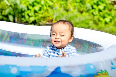 Oğlan yazın ortasında sıcak bir günde evde havuz başında mutlu mesut oynuyor. Gülümsemenin güzel çocuğu..