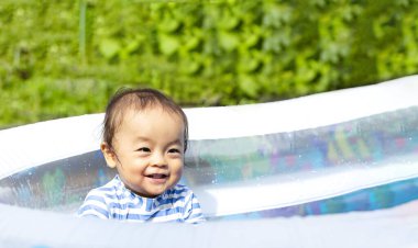 Oğlan yazın ortasında sıcak bir günde evde havuz başında mutlu mesut oynuyor. Gülümseyen sevimli çocuk. Boşluğu kopyala.