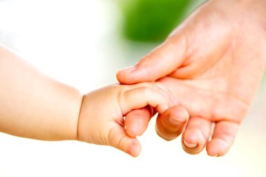 Aile sahnesi, yakın çekim ebeveyn ve bebeğin dışarıda el ele tutuşması..