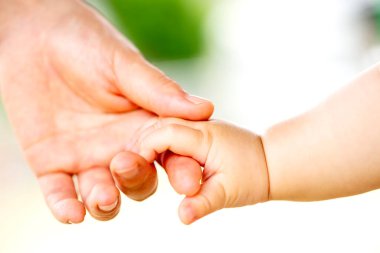 Aile sahnesi, yakın çekim ebeveyn ve bebeğin dışarıda el ele tutuşması..
