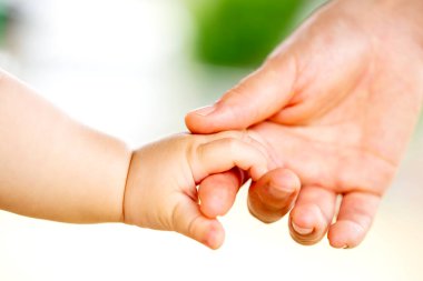 Aile sahnesi, yakın çekim ebeveyn ve bebeğin dışarıda el ele tutuşması..