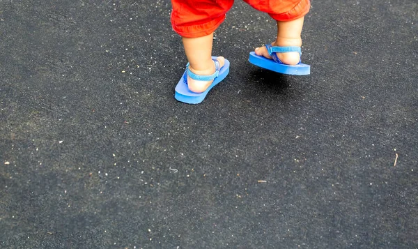 Stopy Dziecka Czerwonych Spodniach Niebieskich Sandałach Plażowych Czarnym Tle Przestrzeni — Zdjęcie stockowe