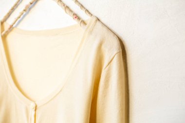 Beyaz elbiseli bir hırka beyaz arka planda asılı duruyor. Yaklaş..