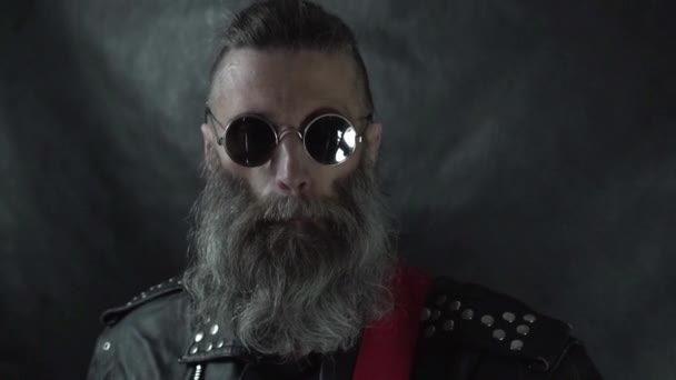 Gros plan de la tête de musicien barbu avec des tempes rasées portant des lunettes rondes et une veste en cuir — Video