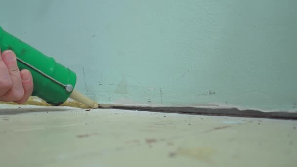 Primer plano de la mano femenina de mediana edad parchando el agujero del piso con sellador de silicona — Vídeos de Stock