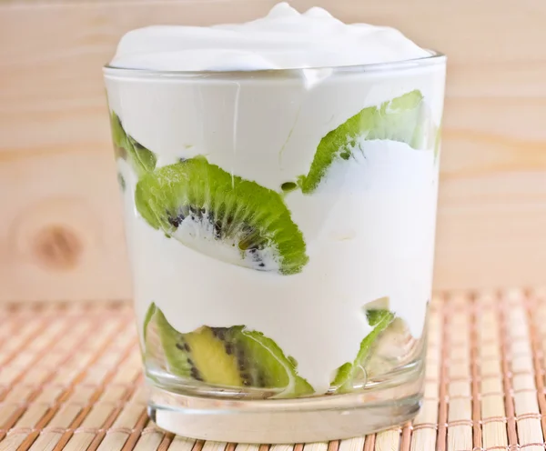Kiwi slices in a glass with cream — Stock Photo, Image