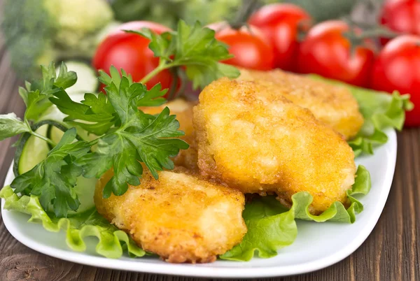 Apetitosas pepitas de pollo con hojas de lechuga — Foto de Stock