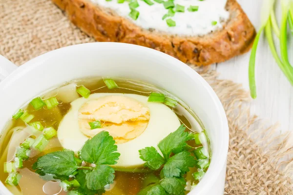 Hot soup with boiled egg on a wooden surface — Stock Photo, Image