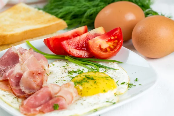 Fried eggs with ham and tomatoes — Stock Photo, Image