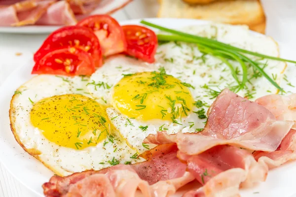 Fried eggs with bacon and green onions — Stock Photo, Image