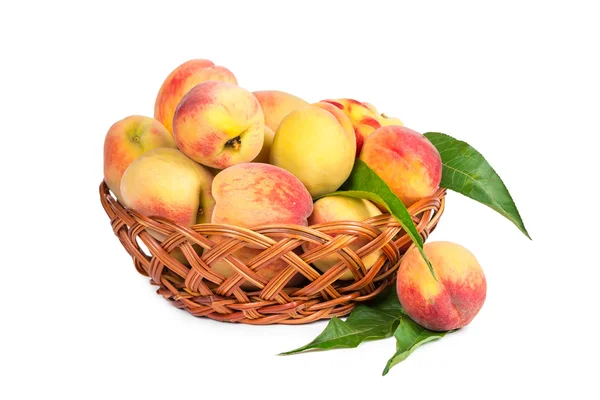 Ripe peaches in a wicker basket — Stock Photo, Image