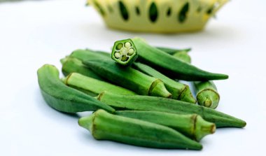 Beyaz arkaplanda çiğ bamya ya ya da kadın parmağı var.