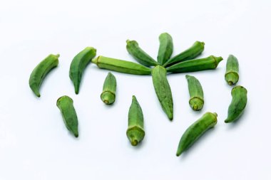 Beyaz arkaplanda çiğ bamya ya ya da kadın parmağı var.