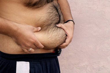 Asyalı şişman bir adamın portresi vücudunu ve koca göbeğini gösteriyor. Obezite kavramı