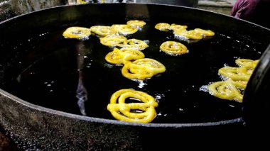 Hintli bir jalebi tezgahta yağ tenceresinde kızarıyor. Jalebi ünlü bir Hint tatlısıdır.