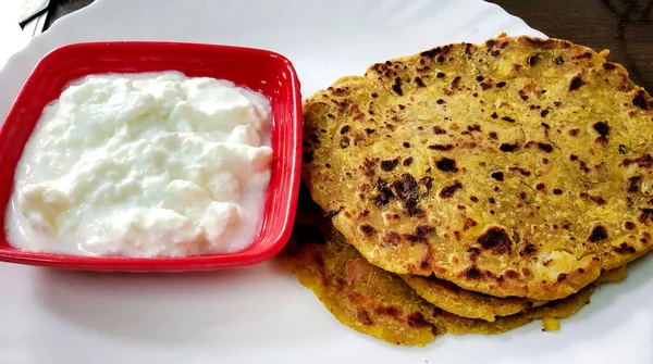 An Indian breakfast dish.Stuffed potato paratha or channa dal paratha served with curd. Selective focus