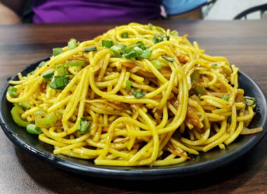 Schezwan Eriştesi ya da sebze Hakka Eriştesi ya da ahşap bir masada servis edilen mısır ve domatesli chow mein. seçici odak