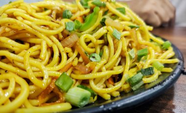 Schezwan Eriştesi ya da sebze Hakka Eriştesi ya da ahşap bir masada servis edilen mısır ve domatesli chow mein. seçici odak