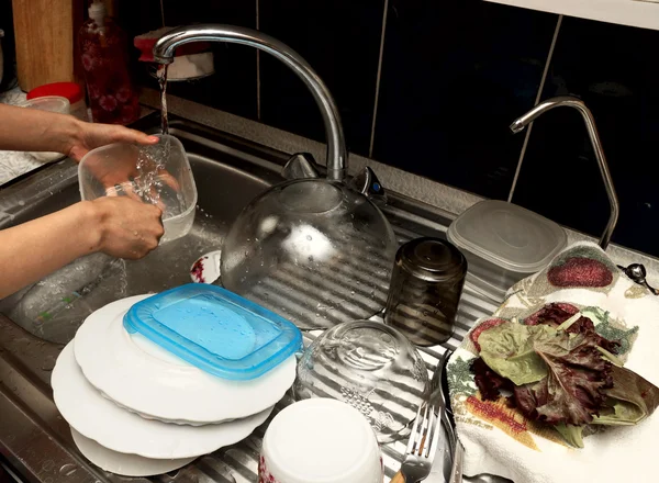 Het meisje wast de gerechten in de keuken — Stockfoto