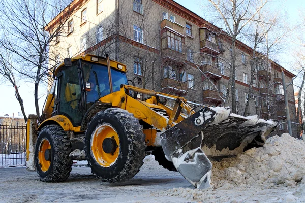 Trekker verwijdert sneeuw op stad straat. — Stockfoto