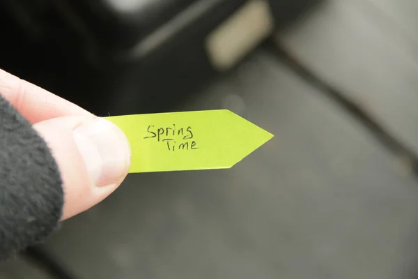 Spring time. The hand holds a tag with a handwritten inscription. — Stock Photo, Image