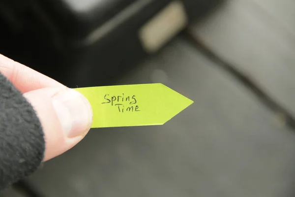 Frühlingserwachen. Die Hand hält einen Anhänger mit einer handschriftlichen Inschrift. — Stockfoto